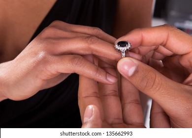 Close Up Of Male Hand Inserting An Engagement Ring Into A Finger