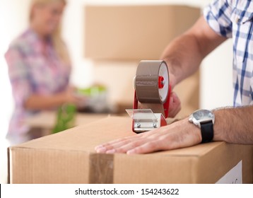 Close up of male hand packing cardboard box, concept moving house