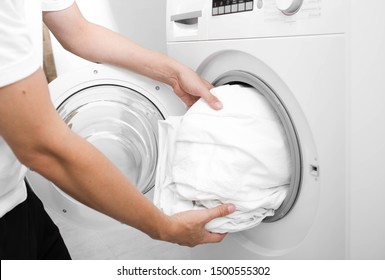 Close Up Of Male Hand Putting A Cloth Into Washing Machine.Wash Linen Bedding