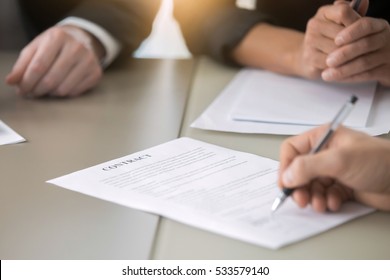 Close up of male hand putting signature, running own small business, have a contract in place to protect it, basics of writing contract, one sentence in a contract can cost a business, handwriting
