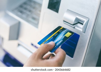 Close up male hand using credit To withdrawing Money from atm Machine. Man insert the atm card into the bank automatic machine.