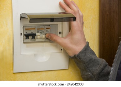 Close up of male hand using an electronic control panel, to switch on electricity at home - Shutterstock ID 242042338