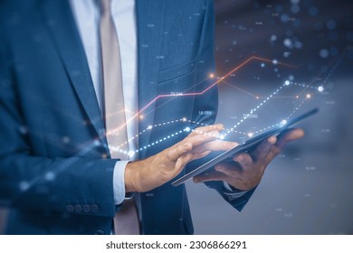 Close up of male hand using tablet with glowing business chart lines with bokeh sparkles on blurry background. Annual report, finance and success concept. Double exposure
