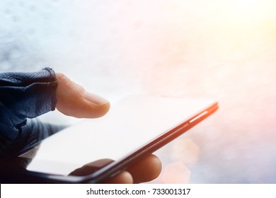 Close up of male hands in a black fingerless leather gloves using smart phone at night on city street, searching or social networks concept, hipster man typing an sms message, toned 
