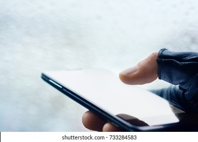 Close up of male hands in a black fingerless leather gloves using smart phone at night on city street, searching or social networks concept, hipster man typing an sms message, toned 
