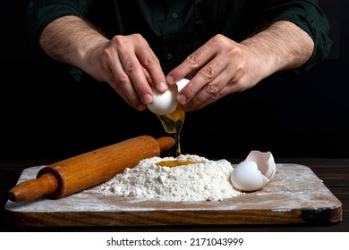 Close up of male hands cracking eggs upon flour, making dough for bread or pastry. Baker man wearing a black outfit in darkness. - Powered by Shutterstock