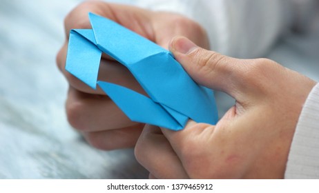 Close Up Male Hands Folding Origami Figure. Man Making Origami From Blue Paper. Paper Folding Art.