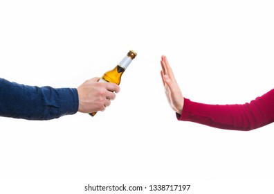 Close Up Of Male Hands Holding A Bottle Of Beer And Proposing It To A Woman Isolated Over White Background. Human Arm Refusal Gesture, Reject Alcohol, Stop Drinking. Bad Habits, Healthcare Concept.