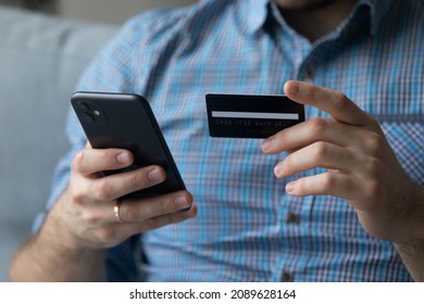 Close up male hands holding cellphone using debit card buying on internet, makes on-line shopping. E-commerce retail services client, funds transfer, spend money through electronic commerce concept