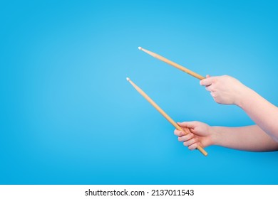 Close up male hands holding drumsticks on an isolated blue background. Concept of drumming lessons, online courses and learning at home. Favourite hobby. Background with copy space. 