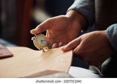 Close up of male hands holding leather piece and inspecting thickness in workshop, copy space - Powered by Shutterstock