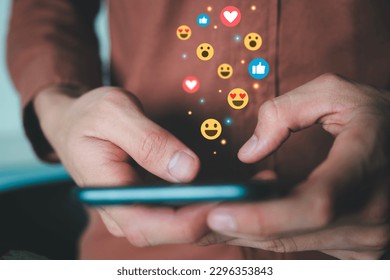 Close up of male hands holding smartphone connecting with people online using social media with illustration hologram of emojis showing and floating. Social media online technology concept. - Powered by Shutterstock