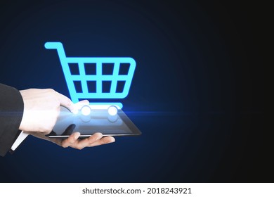 Close up of male hands holding tablet with abstract shopping cart on blue background with mock up place. E-commerce and online shopping concept - Shutterstock ID 2018243921