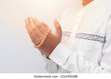 Close up of male hands raising and praying with islamic beads. Religion concept