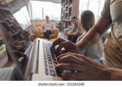 close up of male hands while typing on laptop computer in modern office