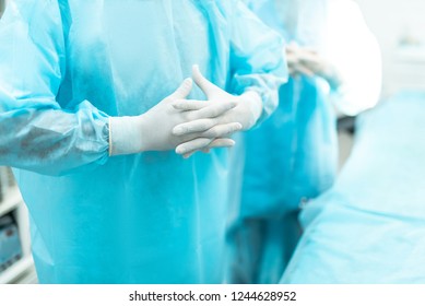 Close Up Of Male Hands In White Sterile Gloves. Surgeon Wearing Blue Surgical Gown