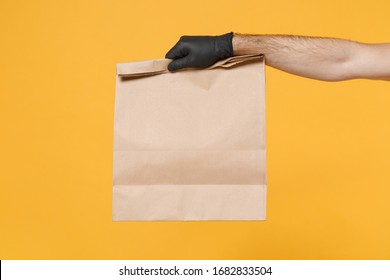 Close up male hold in hand glove brown clear empty blank craft paper bag for takeaway isolated on yellow background. Packaging template mockup. Delivery service concept. Copy space Advertising area - Powered by Shutterstock