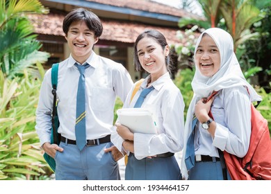 close up of a male Indonesian high school student and two female high school students wearing a school bag and smiling with the camera - Shutterstock ID 1934464157