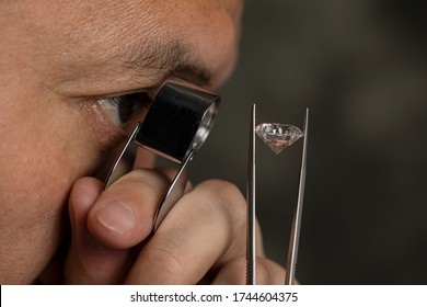 Close up male jeweller. Jeweller looking diamond though loupe. Cut and polished diamond. Big size diamond. Brilliant, magnifier, tweezers. Diamond expert.