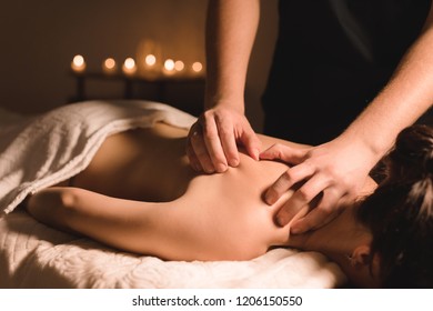 Close Up Male Manual Worker Doing Spa Massage To A Young Girl In A Dark Room