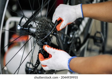 close - up of the male mechanic working in the bicycle repair shop, mechanic repairing bike using a special tool, wearing protective gloves. Bike Maintenance Concept. - Powered by Shutterstock