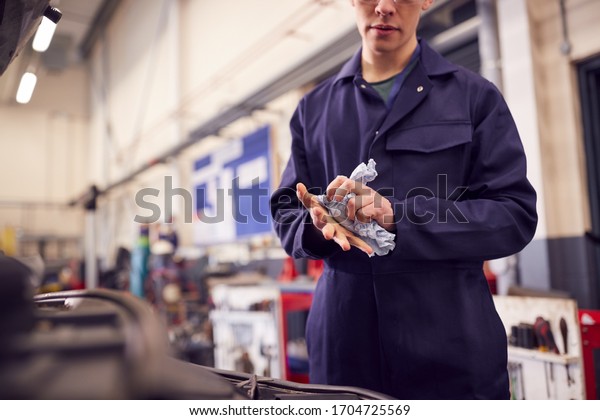 Close Up Of Male Motor Mechanic Wiping Hands\
After Working On Car Engine In\
Garage