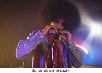 Close up of male musician playing mouth organ in nightclub - Powered by Shutterstock