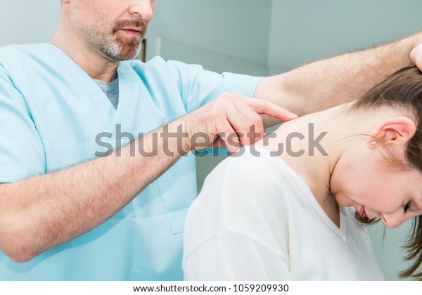 Close up Male neurologist doctor examines\
cervical vertebrae of female patient spinal column in medical\
clinic. Neurological physical examination. Osteopathy,\
chiropractic,\
physiotherapy