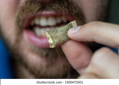 Close up of male putting Swedish snuff (smokeless tobacco) into mouth