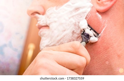 Close Up Of Male Shaving With Razor. Man Shaving His Face With The Razor Blade Through Shave Foam. Men Skin Care Concept.