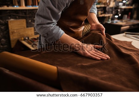 Close up of a male shoemaker working with leather textile at his workshop