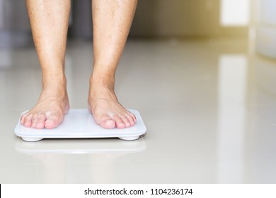 Close up male standing on floor weight scales.
