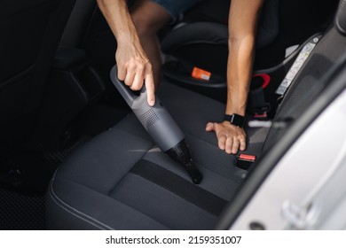 Close up of male using portable vacuum cleaner in her car. Electrical vacuum in man's hand clean car inside from dust