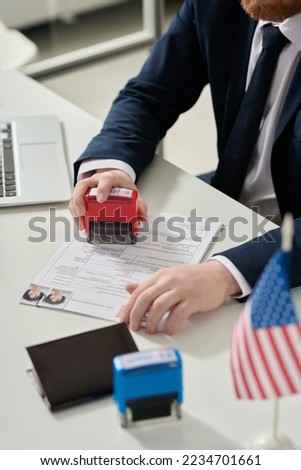 Close up of male worker putting rejected stamp on visa application in US immigration office