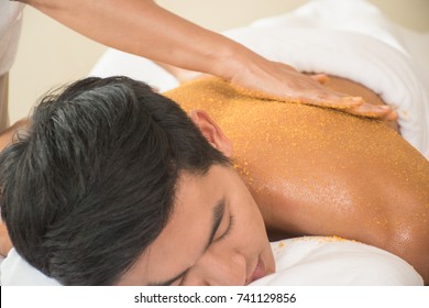 Close Up Man Applying Scrub On Back In Spa Salon.