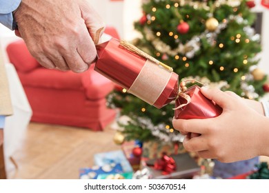 Close Up Of Man And Boys Hands Pulling Christmas Cracker