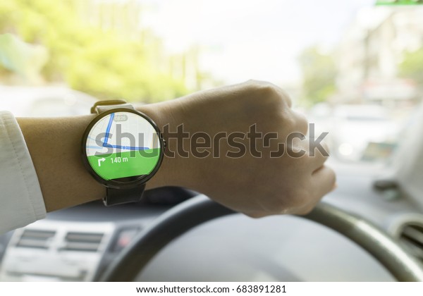 Close up of man in car on
road watching smartwatch and using application navigation map to
destination 