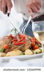 Close Up Of A Man Carving The Roast Chicken At Table