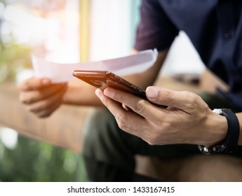 Close up  Man checklist using bank of credit card by mobile phone and pay bills in the office - Shutterstock ID 1433167415
