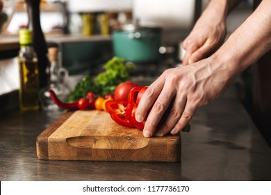 Close Up Of A Man Chef Hands Chopping Vegetables On A Cutting Board At He Kitchen