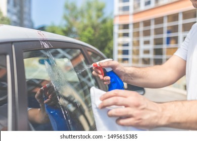 Close up of man cleaning car with cloth and spray bottle, car maintenance concept. Bird shit, drop of bird stain on car window.