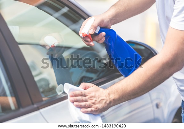 Close up of man cleaning car with cloth and\
spray bottle, car maintenance\
concept.