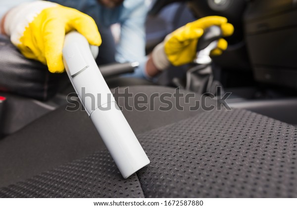Close up\
of man cleaning car seat with vacuum\
cleaner.