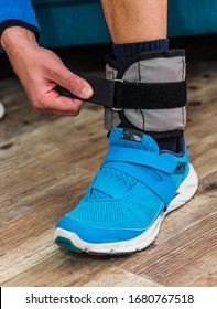 Close Up Of A Man Closing Velcro Strap On Ankle Weight During Home Workout