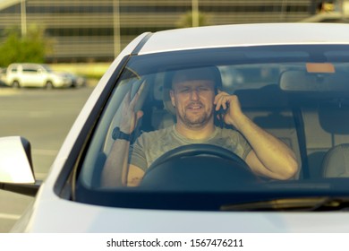 Close up of man commuting to work while using phone.Portrait of young sportsman talking on cellphone in car.Men in grey tshirt using mobile while sitting in car.Picture of smiling man with smartphone.