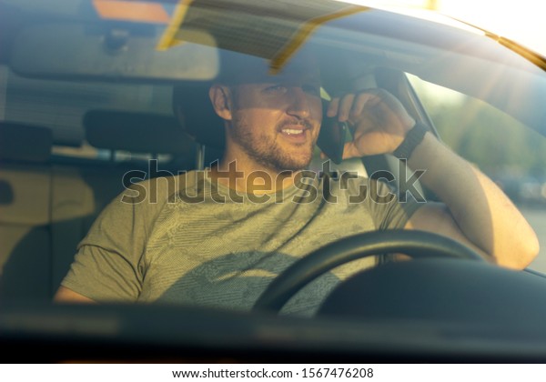 Close up of man commuting to work while using\
phone.Portrait of young sportsman talking on cellphone in car.Men\
in grey tshirt using mobile while sitting in car.Picture of smiling\
man with smartphone.