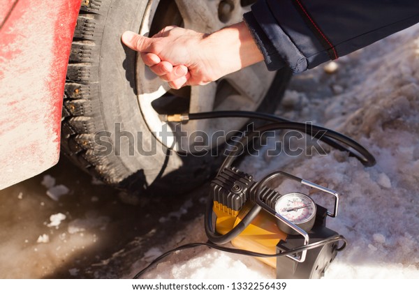 Close up of man crouching on the gas station and\
inflating tire