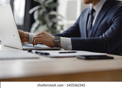 Close Up Of Man In Dark Suit Sitting At The Office Table With Smart Watch On The Wrist And Putting Hand On The Laptop