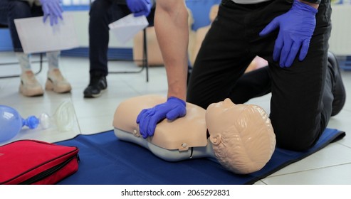 Close Up Man Demonstrating CPR On Teen Mannequin In First Aid Class.