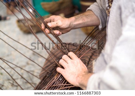 Close up of a man doing basketwork, wickerwork. Basketery. Wicker is a technique for making products woven from any one of a variety of cane-like materials. Traditionally made of material of willow.